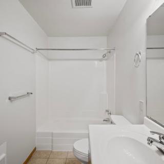 A clean and minimalist bathroom featuring a bathtub, sink, and toilet.