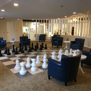 A lounge area featuring a large indoor chess set with comfortable chairs.