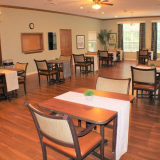 A spacious dining room with multiple tables and chairs, designed for community gatherings.