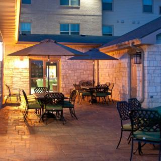 Outdoor patio with tables, chairs, and umbrellas in the evening light.