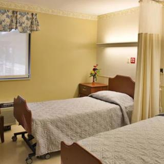 A hospital room with two beds and a privacy curtain.