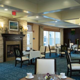 A cozy dining room with a fireplace, elegantly set tables, and large windows.