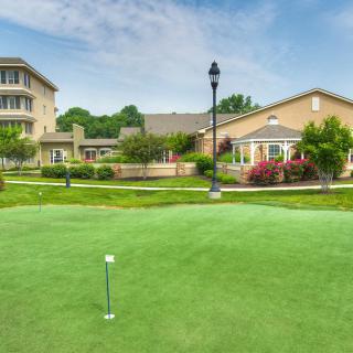 A serene golf course surrounded by buildings and lush greenery under a clear blue sky.