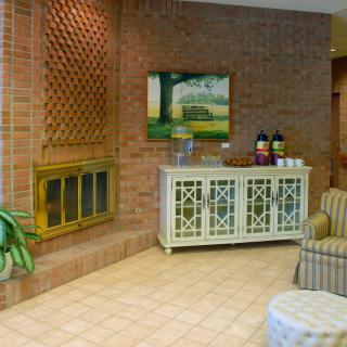 A cozy lobby with a brick fireplace, seating area, and a coffee station.