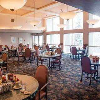 A spacious dining room with tables and chairs, featuring large windows that allow natural light to fill the space.
