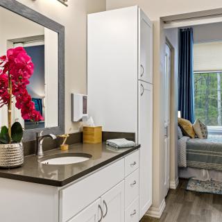 A modern bathroom with a sleek design featuring a sink, mirror, and vibrant orchid decor.