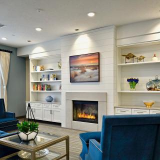 A modern living room with a fireplace, built-in shelves, and blue armchairs creating a cozy atmosphere.