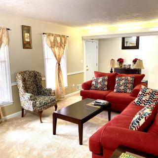 A cozy living room with red sofas, a patterned armchair, and a dark wood coffee table.