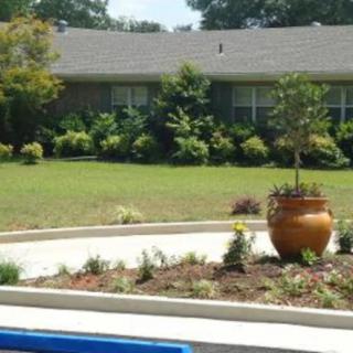 A well-maintained front yard with a large planter and lush greenery outside a house.