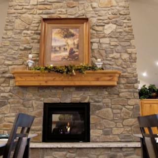 A cozy living room featuring a stone fireplace with a wooden mantle and decorative artwork above.