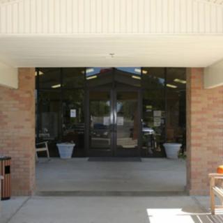 The image shows the entrance of a building with glass doors and brick walls.