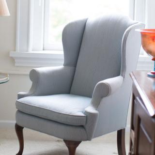 A stylish wingback armchair placed near a window in a cozy living room setting.