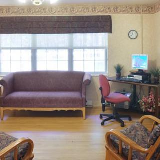 A cozy living room with a sofa, computer desk, and window letting in daylight.