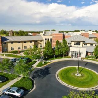 An aerial view of a modern building complex with a circular driveway and surrounding greenery.