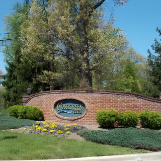 A brick entrance sign surrounded by well-maintained landscaping and trees.