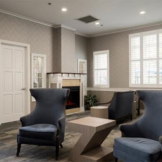 A modern living room with elegant armchairs and a fireplace, featuring neutral tones and contemporary design.