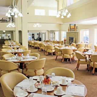 An elegant dining hall with neatly arranged tables and chairs, featuring warm lighting.