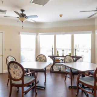 A bright dining area with multiple tables and chairs, featuring large windows that allow natural light to fill the space.