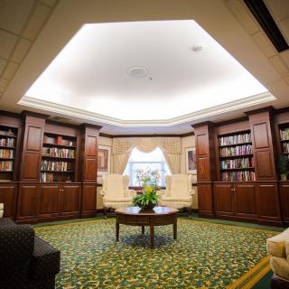 A cozy library interior with wooden bookshelves and a central reading area.