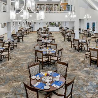 Spacious dining area with neatly arranged tables and elegant chandeliers.
