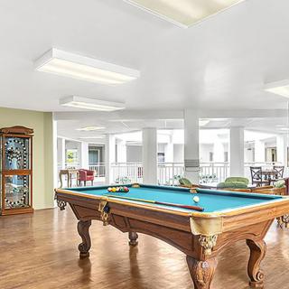 A well-lit game room featuring a pool table and wooden flooring.