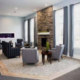 Modern living room with stone fireplace and gray furniture.