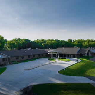 Aerial view of a modern building surrounded by lush greenery and a clear sky.