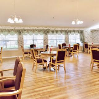A spacious and well-lit dining area designed for seniors, featuring wooden furniture and an inviting atmosphere.