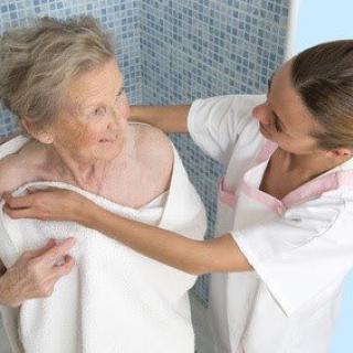 A nurse assisting an elderly woman in a shower, demonstrating compassionate care.