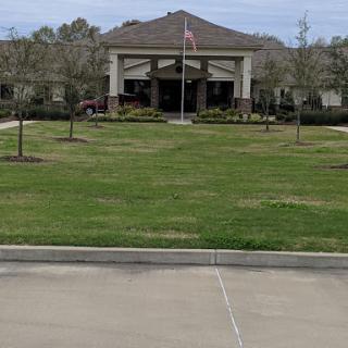 A well-maintained building with a lush green lawn and flag in front.
