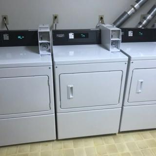 A row of three industrial dryers in a laundromat.