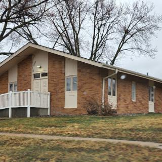 A brick building with a sloped roof and surrounding trees.