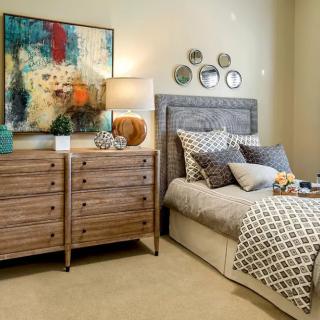 A well-decorated bedroom featuring a cozy bed, modern dresser, and decorative artwork.