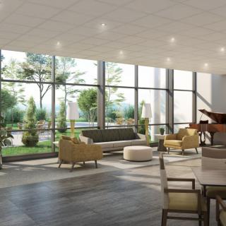 A modern lobby with large windows, ample seating, and a piano, bathed in natural light.
