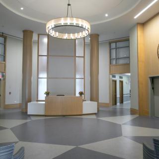 A modern lobby with a central reception desk and a large chandelier.