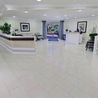 A spacious and modern lobby with a reception desk, seating area, and decorative plants.