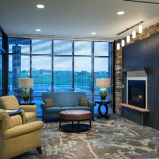 A modern living room with comfortable seating, a fireplace, and large windows offering a scenic view.