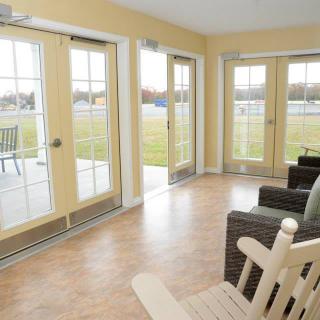 A bright sunroom featuring glass doors and comfortable furniture with a view of the patio.
