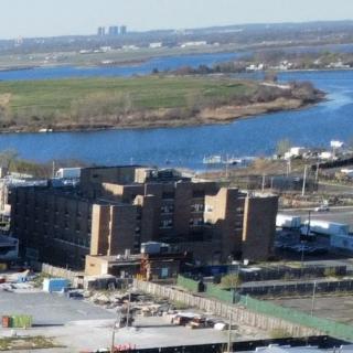 A view of a riverside urban area with buildings and greenery in the background.