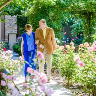 A couple walking together through a beautiful flower garden on a sunny day.