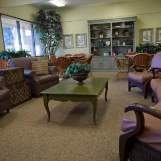 A cozy living room with sofas, armchairs, and a coffee table surrounded by decorations and bookshelves.