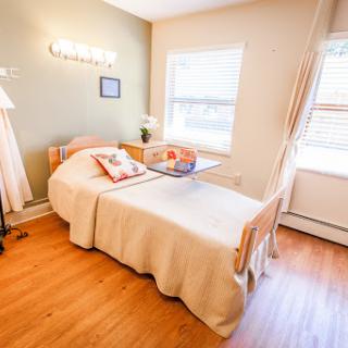 A cozy and well-lit bedroom featuring a single bed and warm wooden flooring.