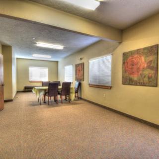 A spacious conference room with a large table and chairs, featuring artwork on the walls.