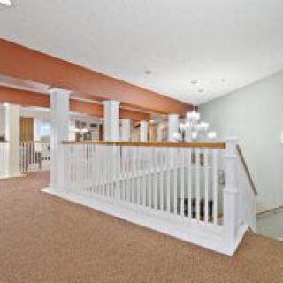A modern interior hallway featuring a staircase with white railings and contemporary lighting.