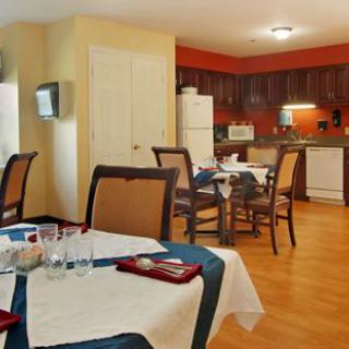 A cozy kitchen and dining area with wooden floors, featuring a neatly set table and modern appliances.
