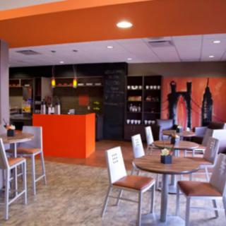 A modern cafe interior with vibrant orange accents and contemporary seating arrangements.