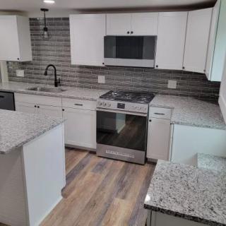 A modern kitchen featuring white cabinets, stainless steel appliances, granite countertops, and a subway tile backsplash.