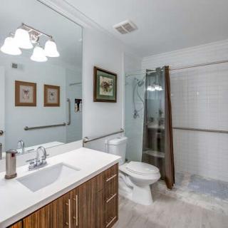 A modern bathroom interior with a large mirror, sink, and a glass-enclosed shower.