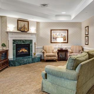 A cozy living room featuring a fireplace, sofa, and armchairs with elegant decor.
