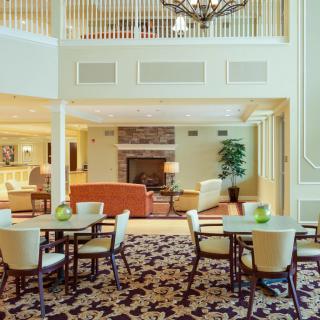A spacious and elegantly designed lobby with seating areas, tables, and a chandelier.